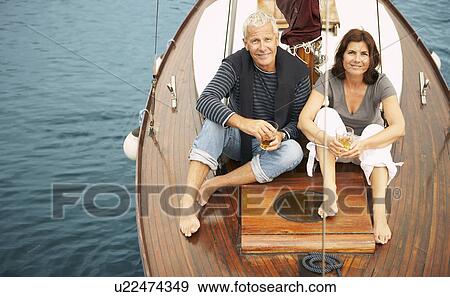 Stock Photo - Middle aged couple drinking on boat. Fotosearch