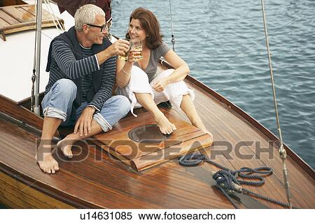 Stock Photography - Middle aged couple drinking on boat. Fotosearch