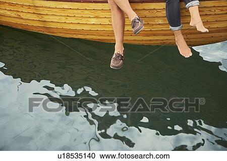 Stock Image - Middle aged couple on boat (feet only). Fotosearch