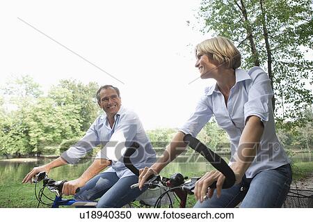 Middle aged couple riding bicycles View Large Photo Image Stock Image - Middle aged couple riding bicycles. Fotosearch