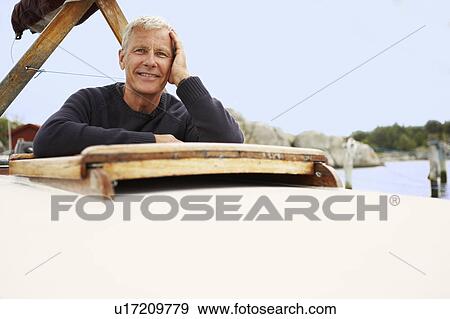 Stock Photo - Middle aged man on old boat. Fotosearch
