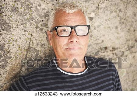 Stock Image - Middle aged man on rocks portrait. Fotosearch