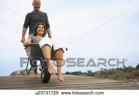Middle aged woman pushed in wheel barrow View Large Photo Image Stock Photo - Middle aged woman pushed in wheel barrow. Fotosearch