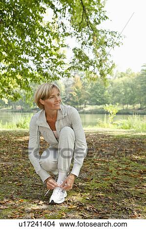 Middle aged woman tying her jogging shoe View Large Photo Image Picture - Middle aged woman tying her jogging shoe. Fotosearch
