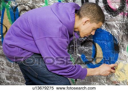 Stock Photography - Mixed race Teenager doing graffiti. Fotosearch