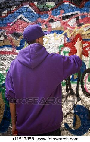 Stock Photo - Mixed Race Teenager spray painting. Fotosearch