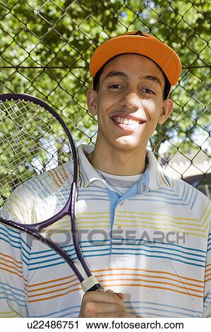 Stock Image - Mixed race Teenager with tennis racket. Fotosearch