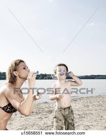 Stock Image - Mother and child blow bubbles. Fotosearch