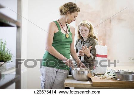 Picture - mother and daughter in kitchen. Fotosearch