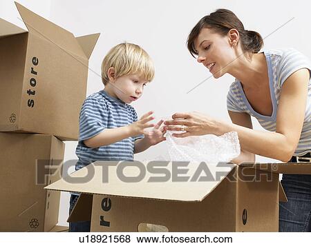 Stock Photo - Mother and son unpacking moving boxes. Fotosearch