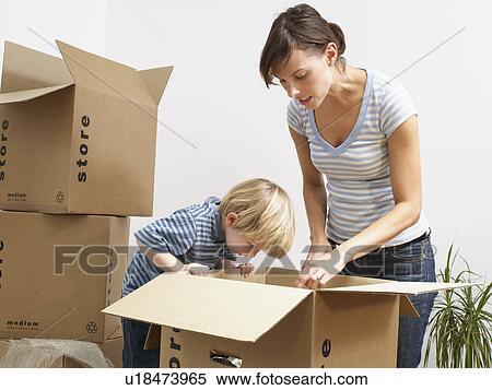 Stock Photography - Mother and son unpacking moving boxes. Fotosearch