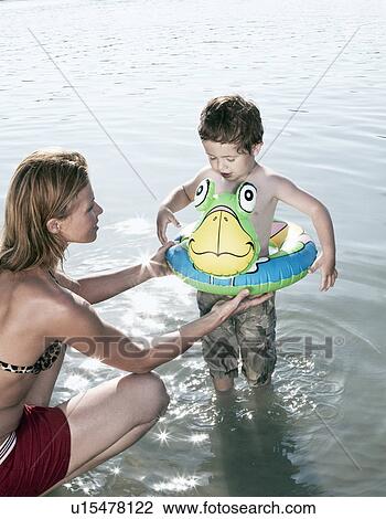 Mother fitting child's swimming ring View Large Photo Image Stock Image - Mother fitting child's swimming ring. Fotosearch