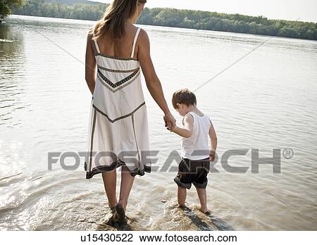 Stock Image - Mother guiding child in river. Fotosearch