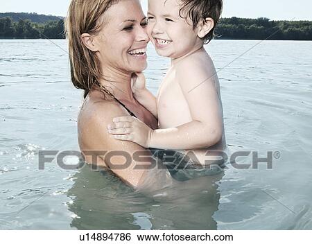 Mother holding child in river View Large Photo Image Stock Photograph - Mother holding child in river. Fotosearch