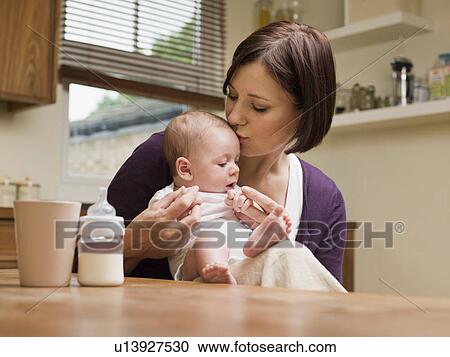 Mother kissing her baby in the kitchen View Large Photo Image Stock Image - Mother kissing her baby in the kitchen. Fotosearch
