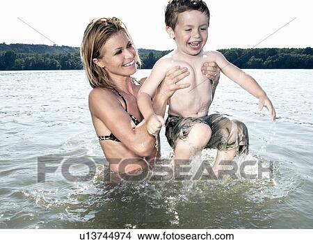 Picture - Mother lifting child in river. Fotosearch
