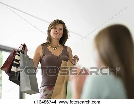 Picture - mother showing shopping to teenage girl. Fotosearch