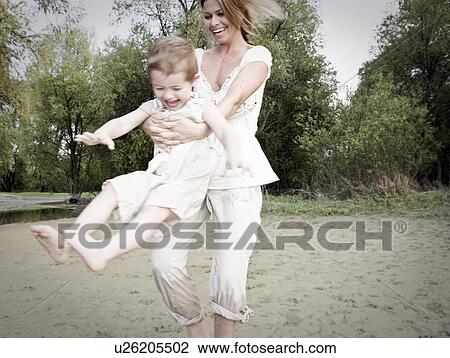 Stock Image - Mother swinging child. Fotosearch