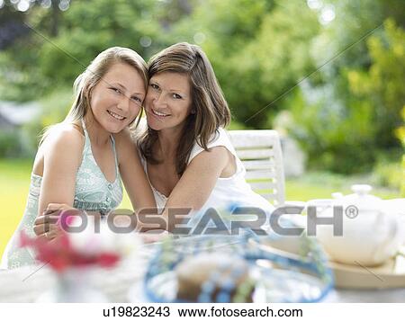 Stock Image - mum and daughter take tea in garden. Fotosearch