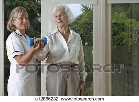 Stock Image - Nurse helping woman with exercises. Fotosearch