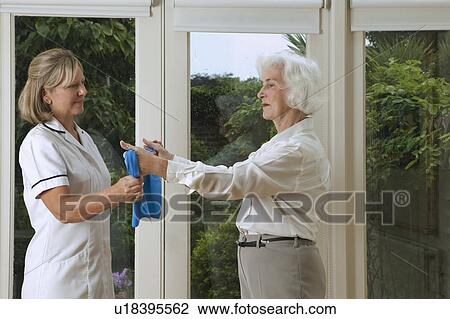 Stock Image - Nurse helping woman with exercises. Fotosearch