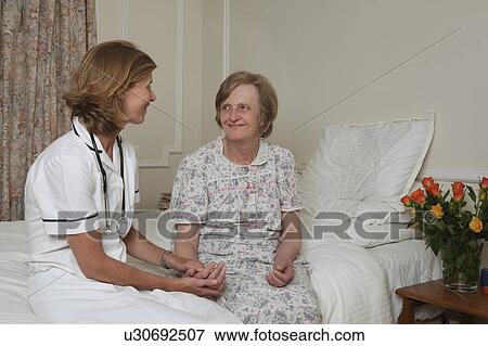 Stock Photo - Nurse holding elderly woman's hand. Fotosearch