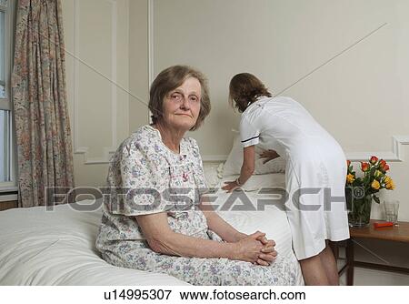 Stock Photo - Nurse making bed for elderly woman. Fotosearch