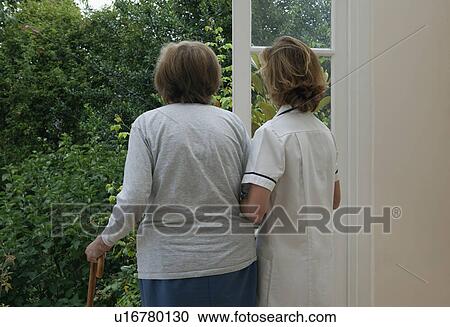 Stock Image - Nurse supporting elderly woman. Fotosearch