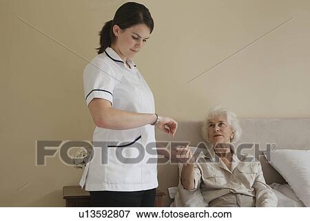 Stock Photo - Nurse taking pulse of elderly woman. Fotosearch