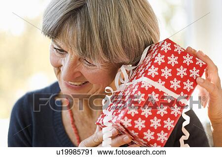 Old woman holding ear against present View Large Photo Image Stock Image - Old woman holding ear against present. Fotosearch