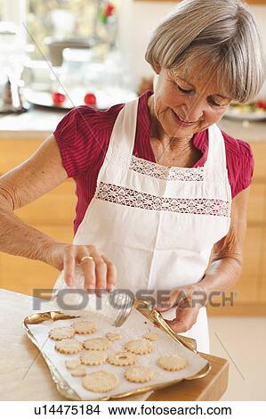 Picture - old woman preparing biscuits. Fotosearch