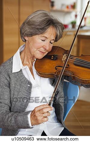 Stock Image - old woman tuning violin. Fotosearch