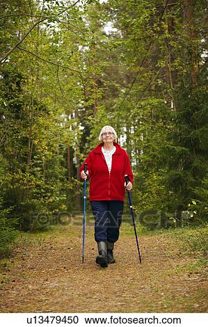 Stock Image - Older woman hiking in forest. Fotosearch