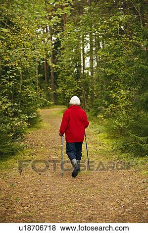 Stock Photo - Older woman hiking in forest. Fotosearch