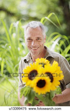 Stock Photography - outdoor portrait of a man and sunflowers. Fotosearch