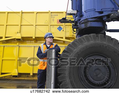 Stock Image - Port Worker With Heavy Machinery. Fotosearch