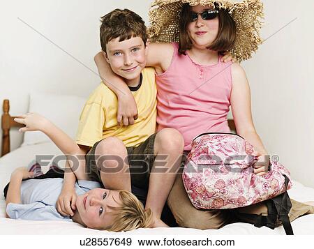 Portrait of 3 children sitting on a bed View Large Photo Image Stock Photo - Portrait of 3 children sitting on a bed. Fotosearch