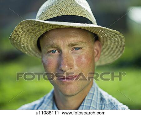 Stock Image - Portrait of a smiling man in a straw hat. Fotosearch