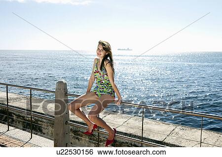 Portrait of girl sitting on railing View Large Photo Image Stock Photograph - Portrait of girl sitting on railing. Fotosearch