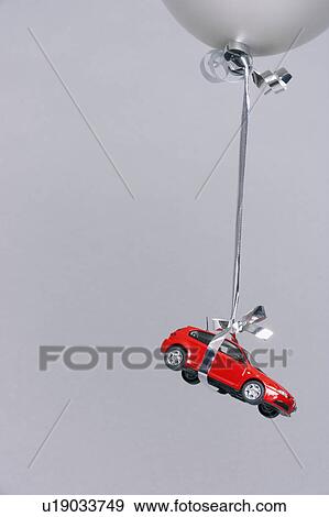 Stock Photo - Red car carried by a grey balloon. Fotosearch