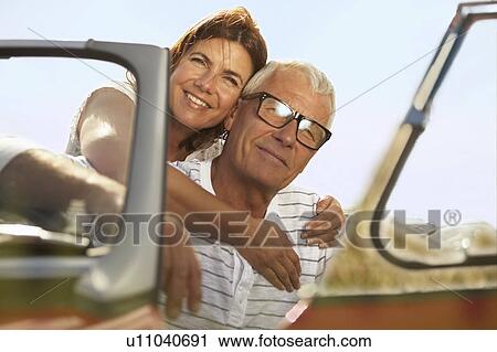 Stock Image - Senior couple embracing in sports car. Fotosearch