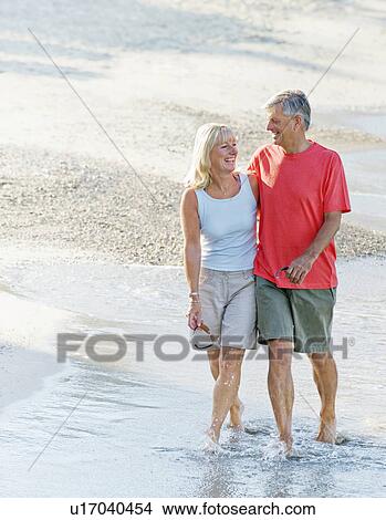 Picture - Senior couple walk along the beach. Fotosearch