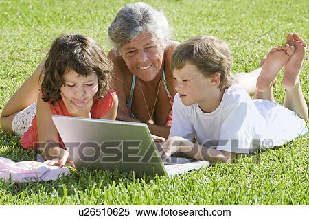 Stock Photography - Senior female with children on laptop. Fotosearch
