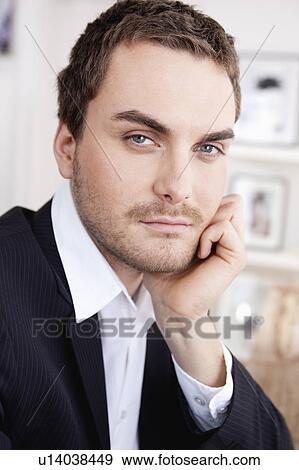 Stock Photo - serious looking man resting chin on hand. Fotosearch