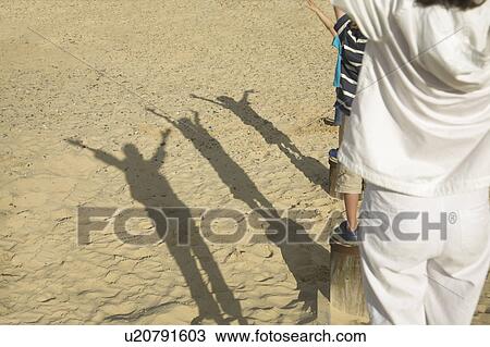 Stock Image - Shadows of people on groynes. Fotosearch