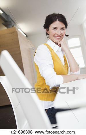 Stock Photo - smiling woman sitting at table. Fotosearch