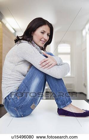 smiling woman sitting on table View Large Photo Image Stock Image - smiling woman sitting on table. Fotosearch
