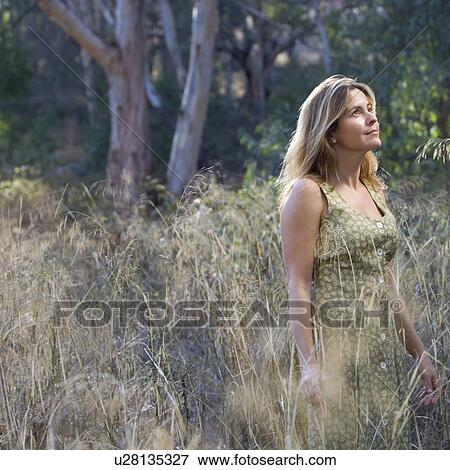 Stock Photo - Smiling woman standing in a field. Fotosearch
