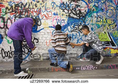 Teenage gang doing graffiti on a wall View Large Photo Image Stock Photograph - Teenage gang doing graffiti on a wall. Fotosearch