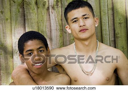 Stock Image - Teenagers bare chested against fence. Fotosearch